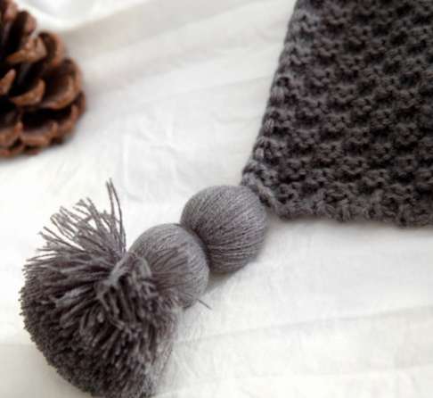 Knitted throw with pom-pom fringe on a sofa