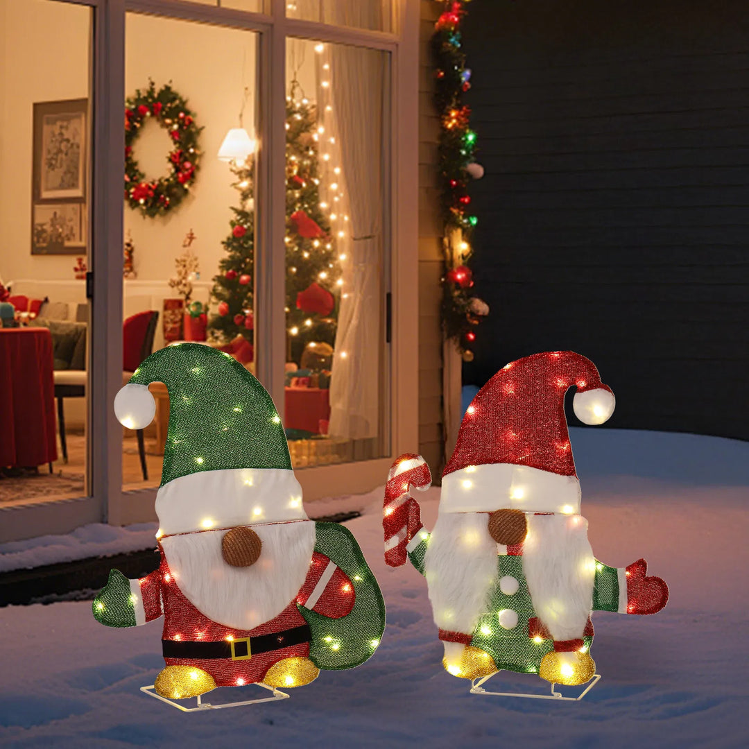 Two lit Christmas gnome figures in garden
